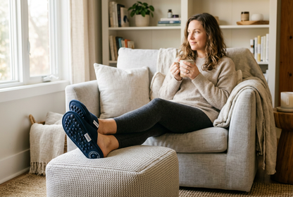 Person relaxing at home wearing acupressure foot massage slippers, cosy living room setting